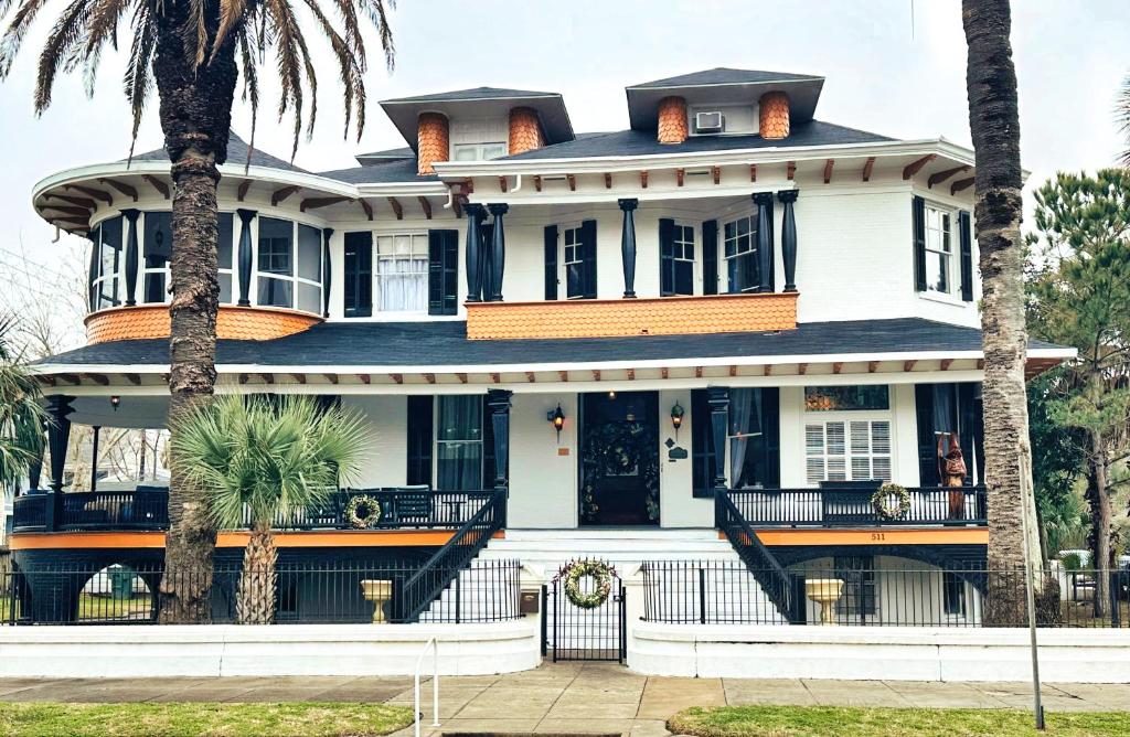uma casa branca com palmeiras em frente em The Mansion on 17th, formerly Schaefer Haus em Galveston