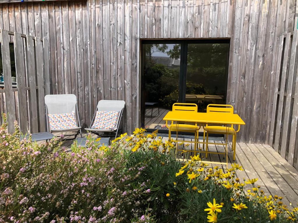 a yellow table and chairs on a deck with flowers at Les Chambres d&#39;Hôtes de Bordustard in Le Palais