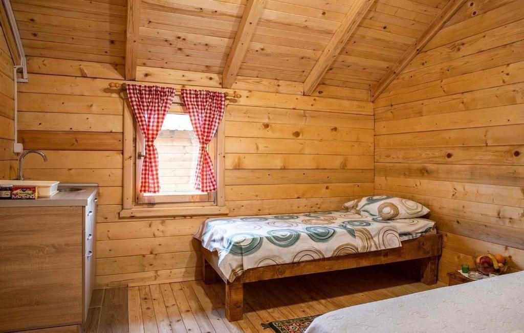 1 dormitorio con 1 cama en una cabaña de madera en Burzan Bungalovi, en Podgorica