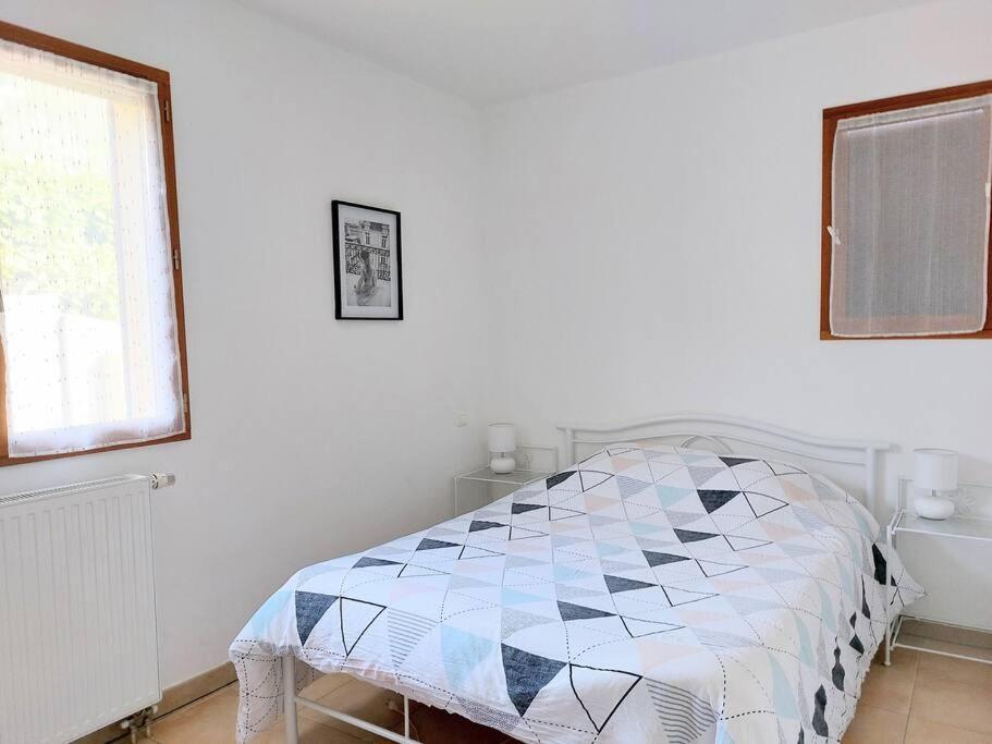 um quarto branco com uma cama com uma colcha em Rez de jardin dans quartier calme et ensoleillé em Saint-André-les-Alpes