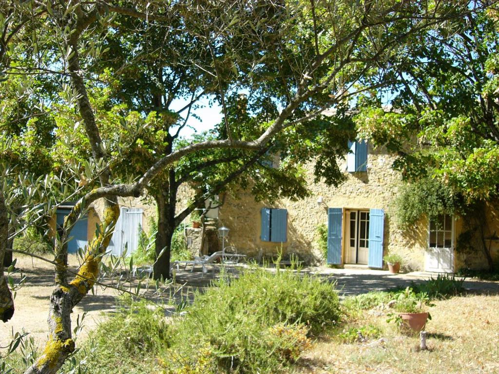 una casa de piedra con una puerta azul y árboles en Mas Boudeissoun - Cœur de cerise - Baignade à 600 m, en Mormoiron