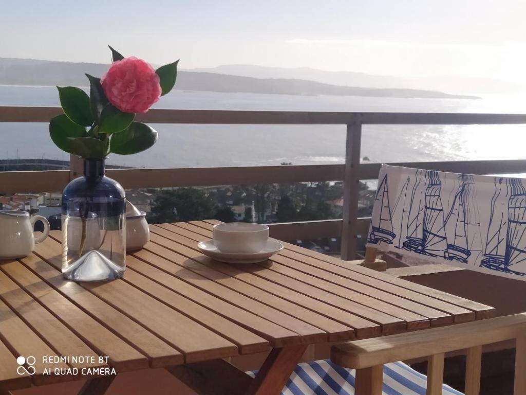 un tavolo di legno con un vaso con un fiore sopra di San Vicente Views a San Vicente do Mar