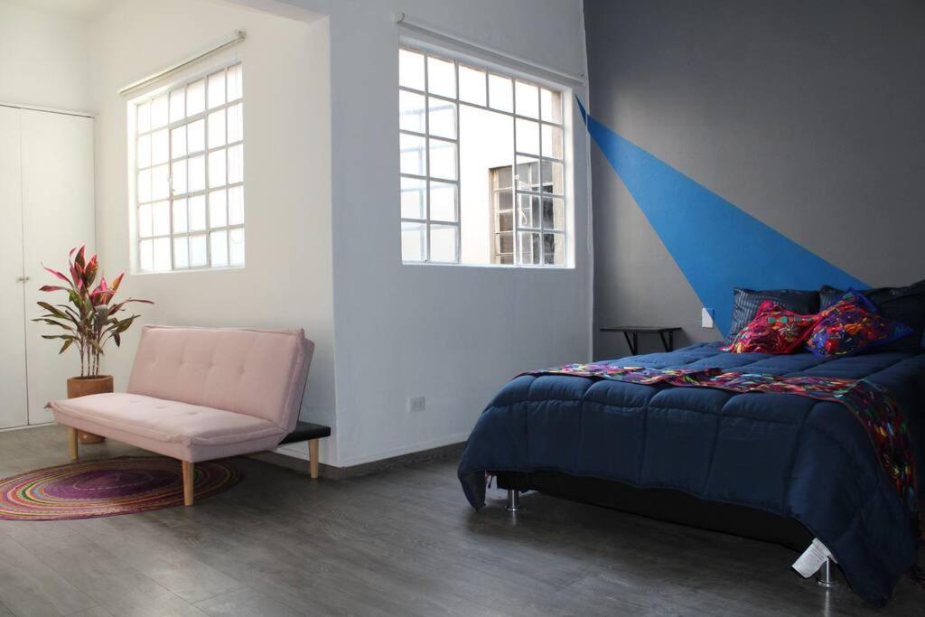 1 dormitorio con 1 cama, 1 silla y ventanas en Am Condesa en Ciudad de México