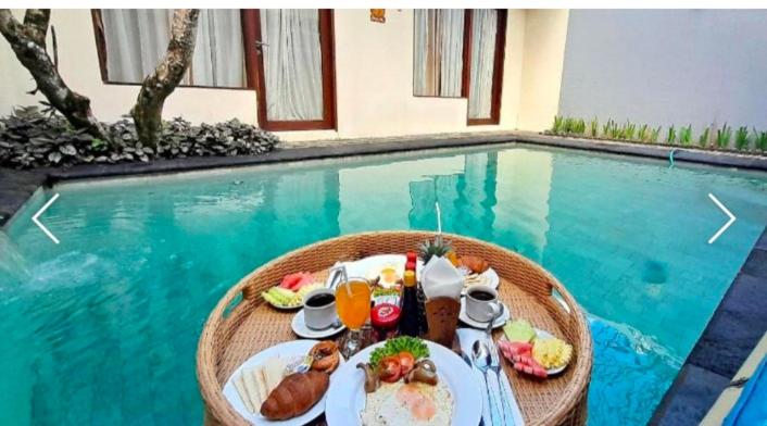 a table with food and drinks next to a swimming pool at One Bedroom Private Pool Kuta in Kuta