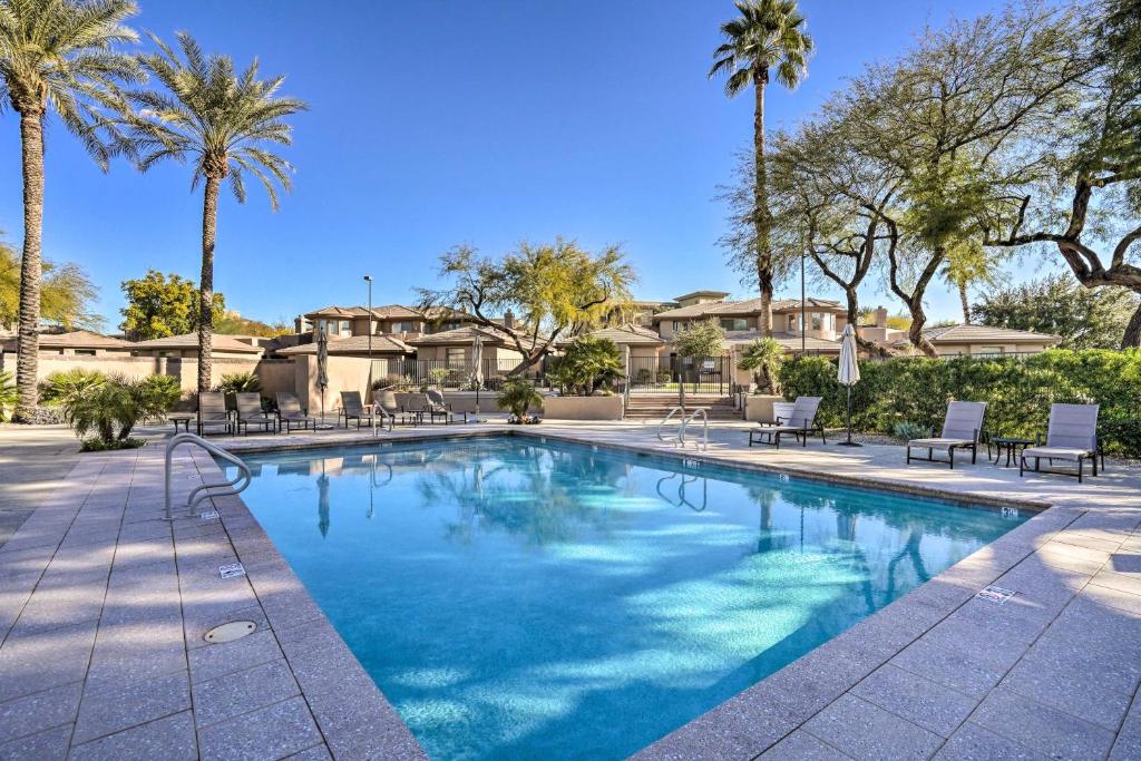 a swimming pool with chairs and palm trees at Elegant Scottsdale Townhome with Heated Pool! in Scottsdale