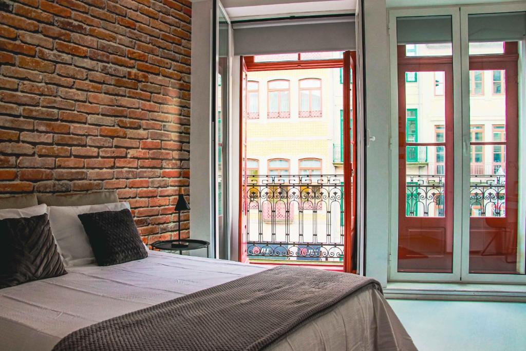 a bedroom with a bed and a brick wall at Hannah's Studios in Porto