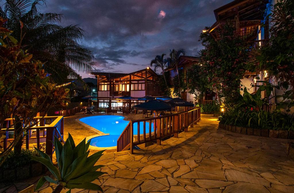 a resort with a swimming pool at night at Hotel Praia do Portinho in Ilhabela