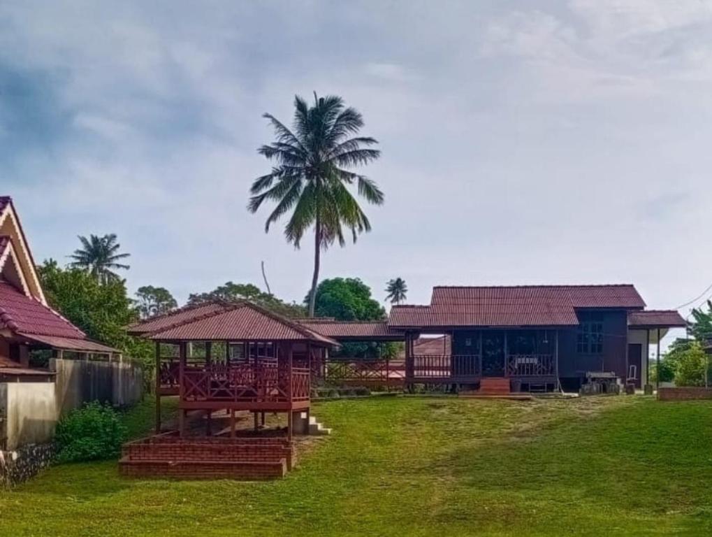 een huis met een palmboom in de tuin bij Kampong Style Homestay Pengkalan Balak - Sea View in Pengkalan Balak