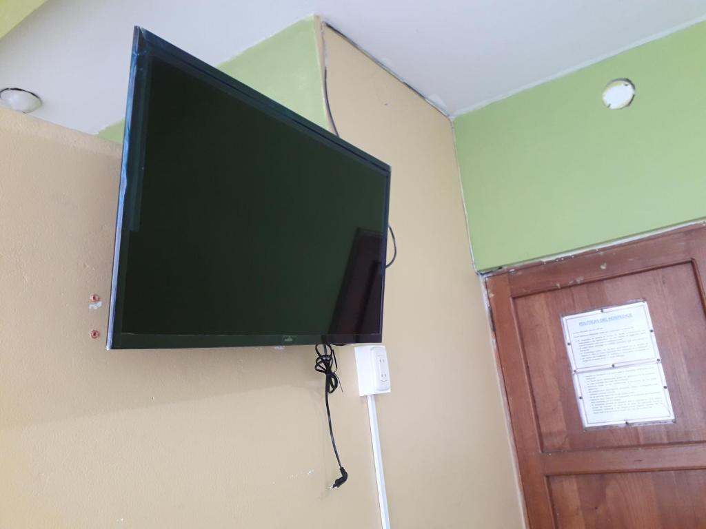 TV de pantalla plana colgada en una pared junto a una puerta en Hospedaje callao, en Moyobamba