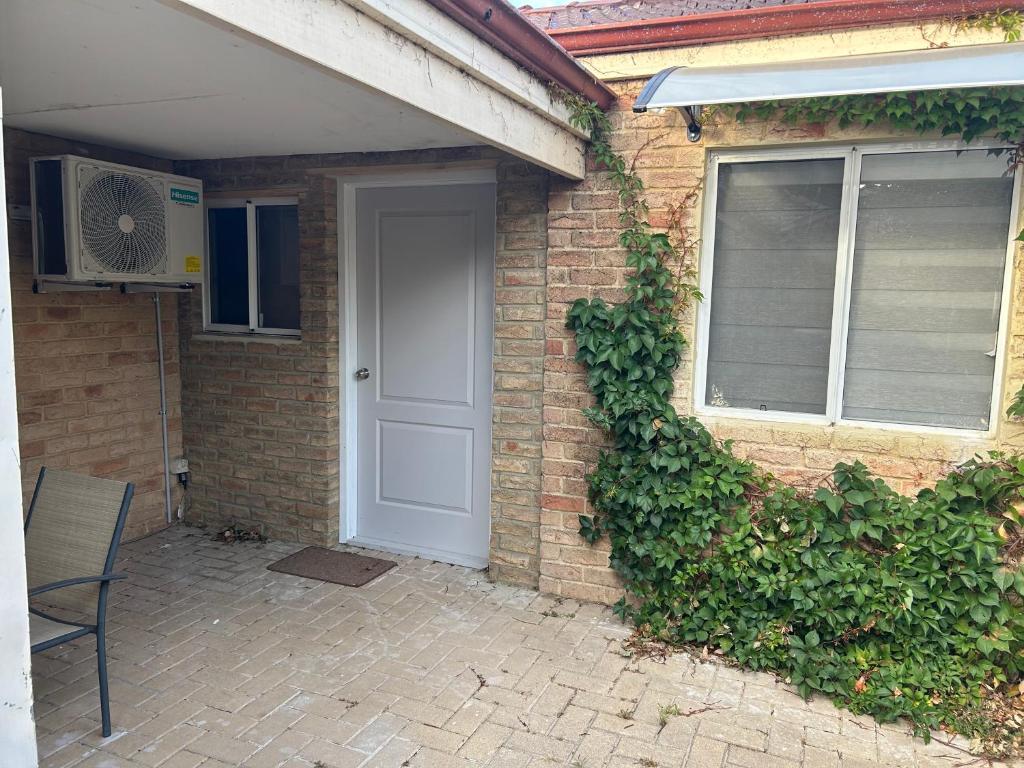 a brick house with a white door and a window at Lovely large studio in canning vale in Perth