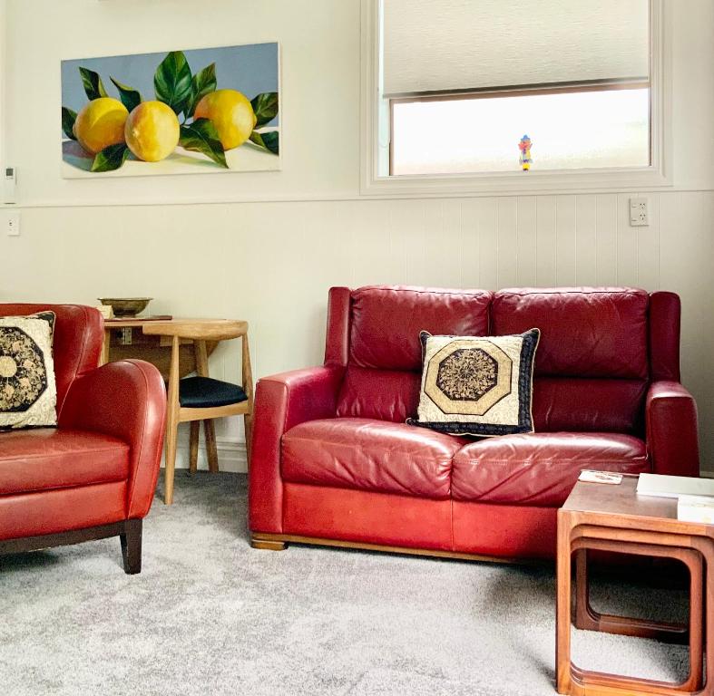 un sofá rojo y una silla en la sala de estar en The Partchery Devonport, en Auckland