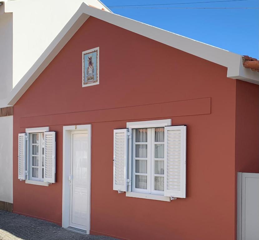 ein rotes Haus mit weißen Fensterläden in der Unterkunft Torreira Vacation Homes - Ria House in Torreira