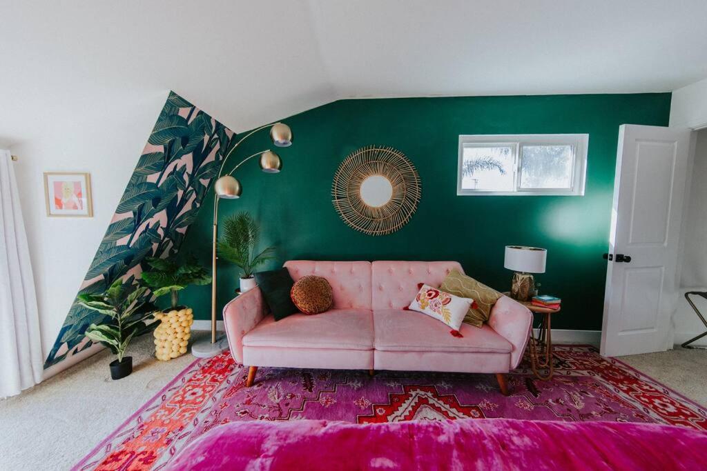 sala de estar con sofá rosa y pared verde en Pink Paradise Inn - 5 BR Fun Retro Home w/ Pool, en Oceanside