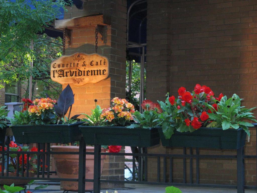 un grupo de flores expuestas frente a un edificio en L'Arvidienne Couette et Café en Quebec