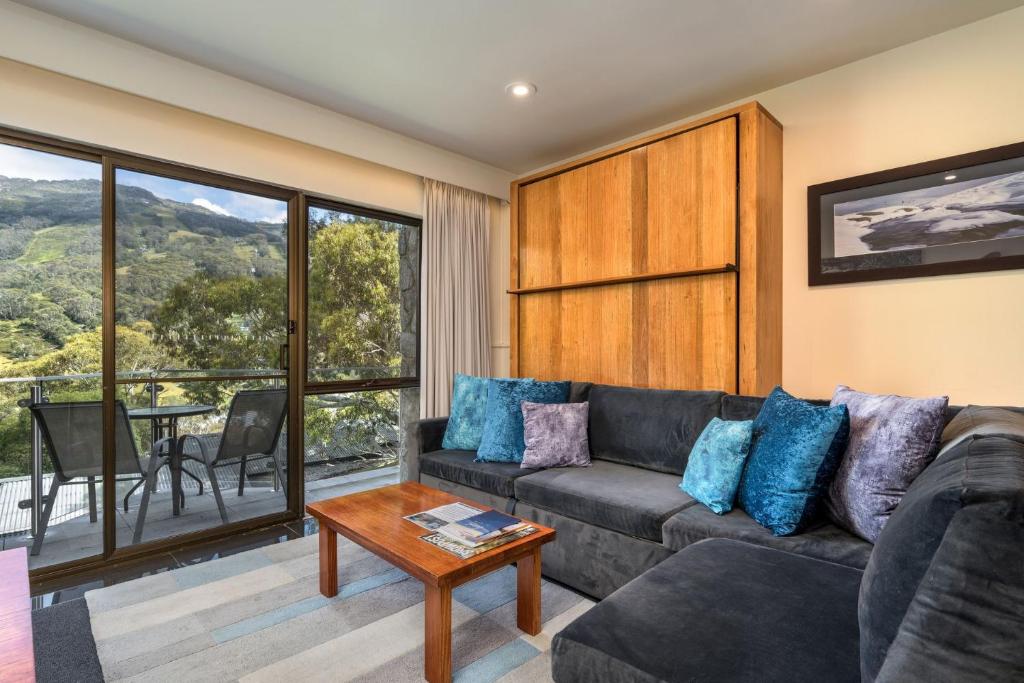 a living room with a couch and a table at Lantern 1 Bedroom Balcony with mountain View in Thredbo