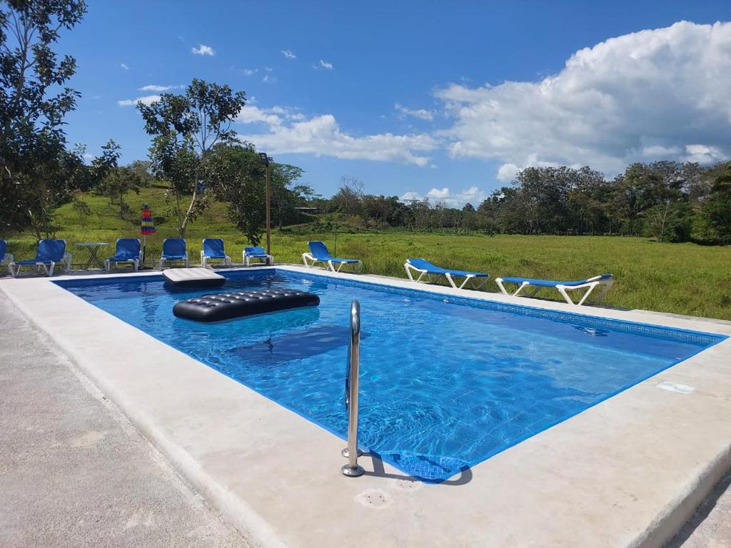 a swimming pool with chairs in a field at Residencia las brisas Griegas in Quepos