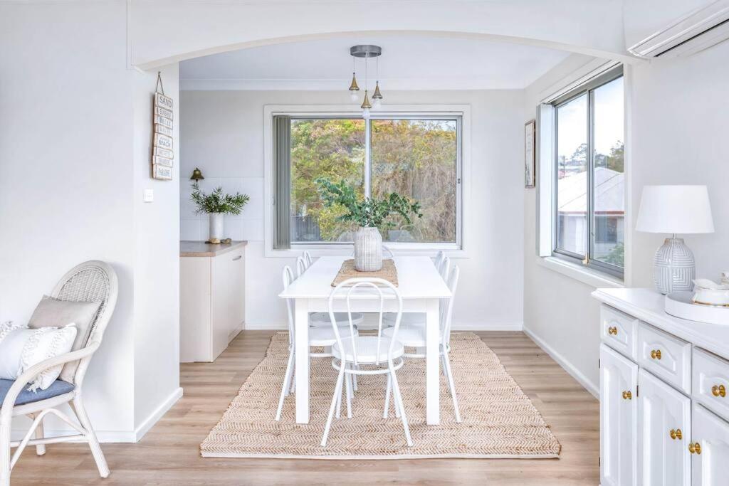 a white dining room with a white table and chairs at Family Tides - Old Bar Holiday Rentals in Old Bar