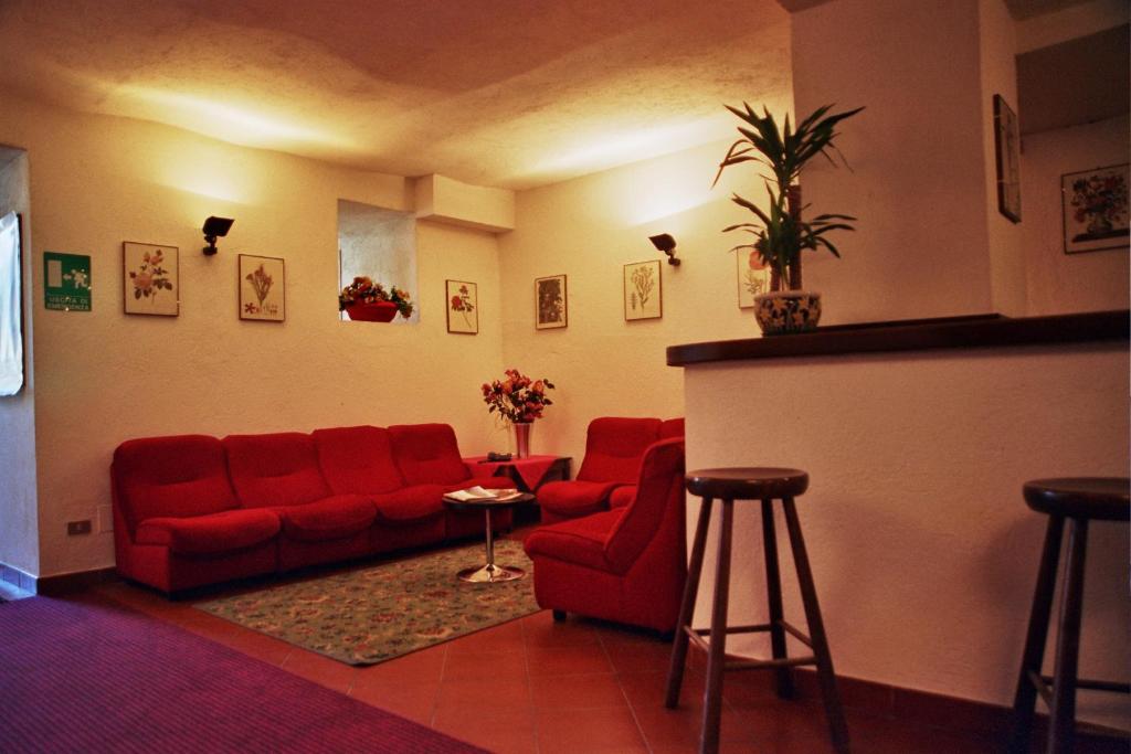 a living room with a red couch and two chairs at Hotel Biancaneve in Sestriere