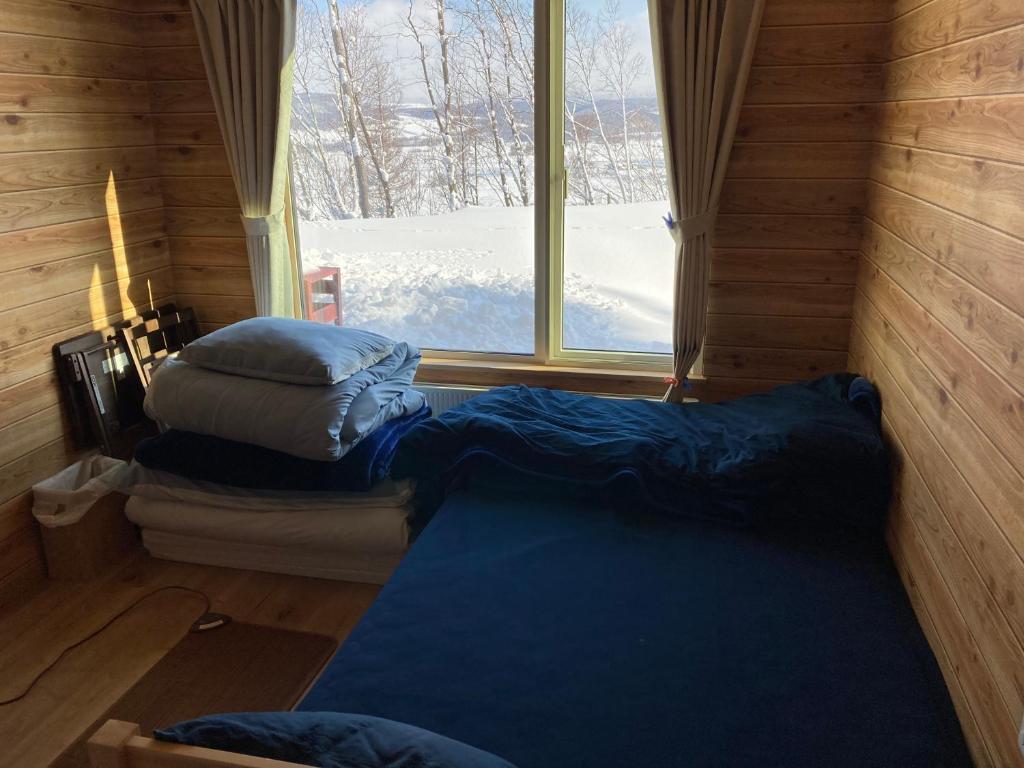 a room with two pillows and a window in a cabin at はるの空 in Biei