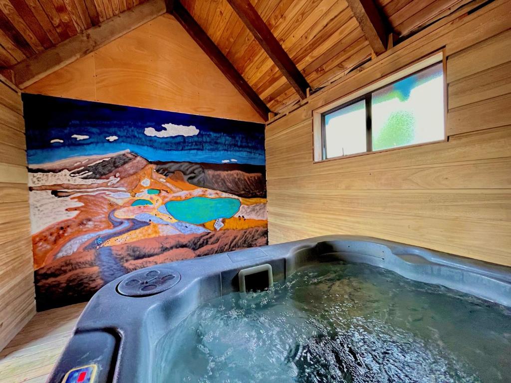 bañera en una habitación con una pintura en la pared en Adventure Lodge and Motels and Tongariro Crossing Track Transport, en National Park