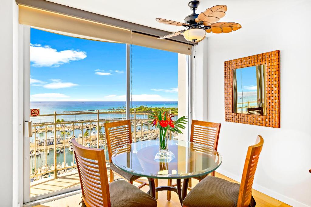 a dining room with a glass table and chairs and a balcony at Ilikai Marina 1BR Condo, Ocean View Haven in Honolulu