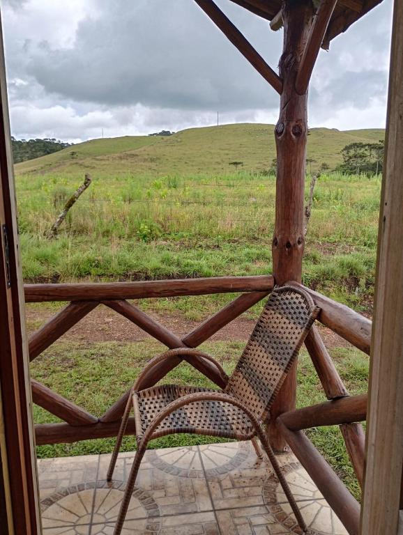 a chair sitting on a porch with a view of a field at Recanto do Cachoeira do Nassuca in Cambará