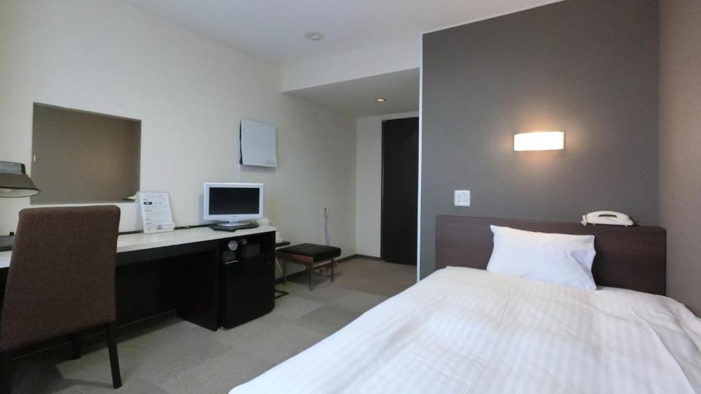 由利本莊市的住宿－Honjo Grand Hotel Vacation STAY 35747，一间卧室配有一张床和一张带电脑的书桌