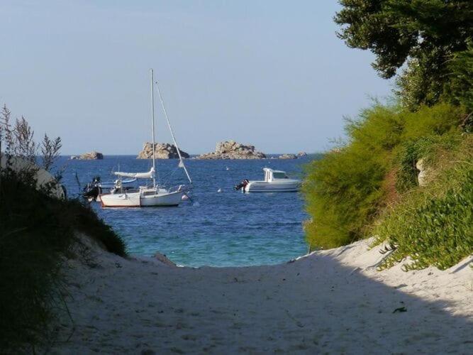 two boats floating in the water near a beach at Premium holiday home in top location with sea view, Plougasnou in Plougasnou