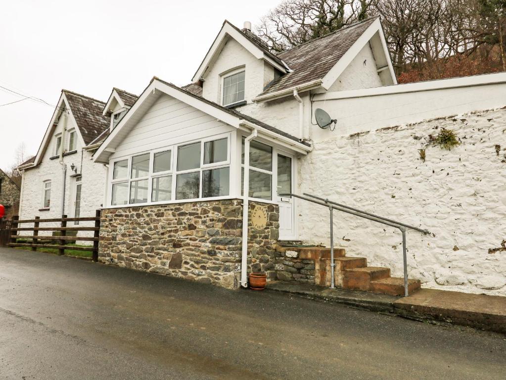 a white house with a stone wall at Tanyrallt Farm in Beulah