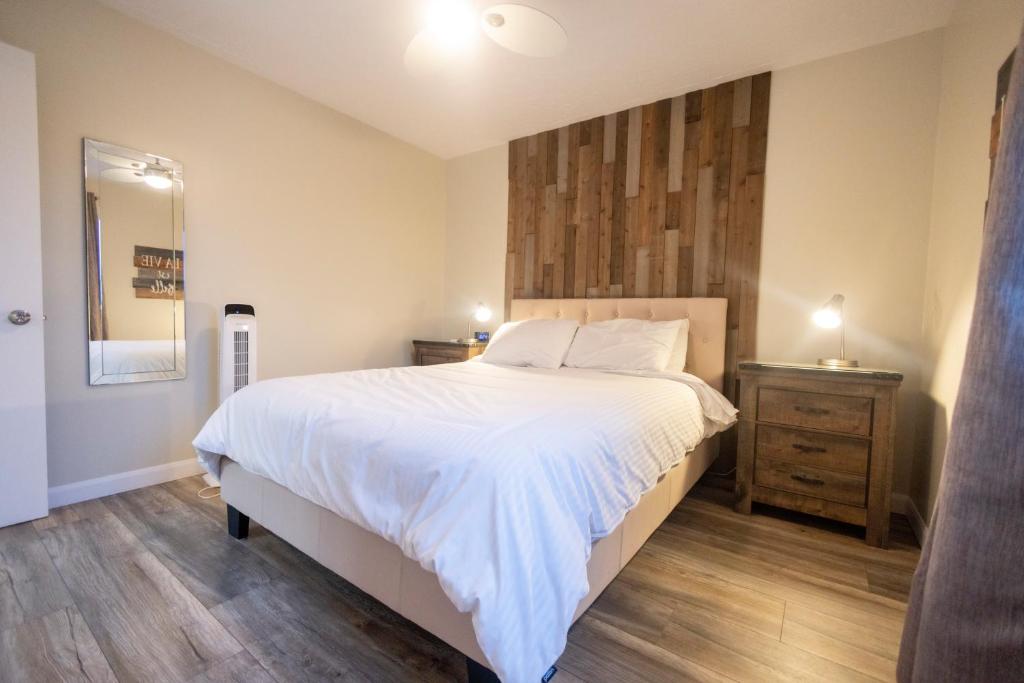 um quarto com uma grande cama branca e piso em madeira em Le Contemporain em Rouyn
