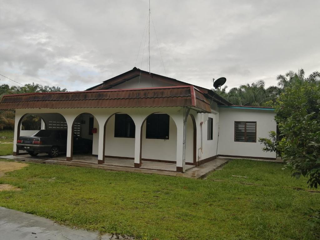 una casa con porche y un camión estacionado en el patio en KJS Homestay, Layang-Layang, Johor, en Kangkar Lanjut