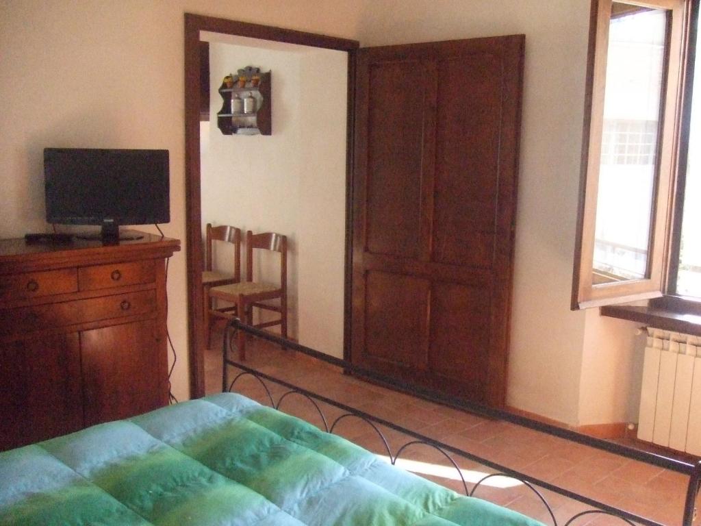 sypialnia z łóżkiem, komodą i telewizorem w obiekcie Appartamento La Palma w mieście San Gimignano