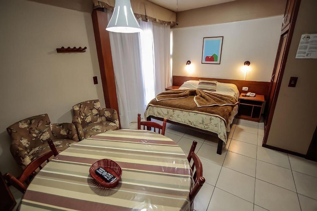 a bedroom with a bed and a table and chairs at Pousada do Serrano - Rua Torta in Gramado
