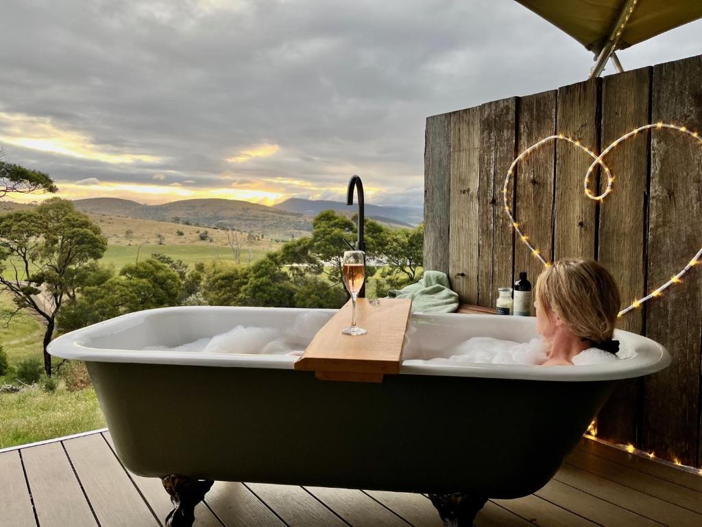 a woman in a bath tub with a glass of wine at Aquila Eco Retreat in Richmond