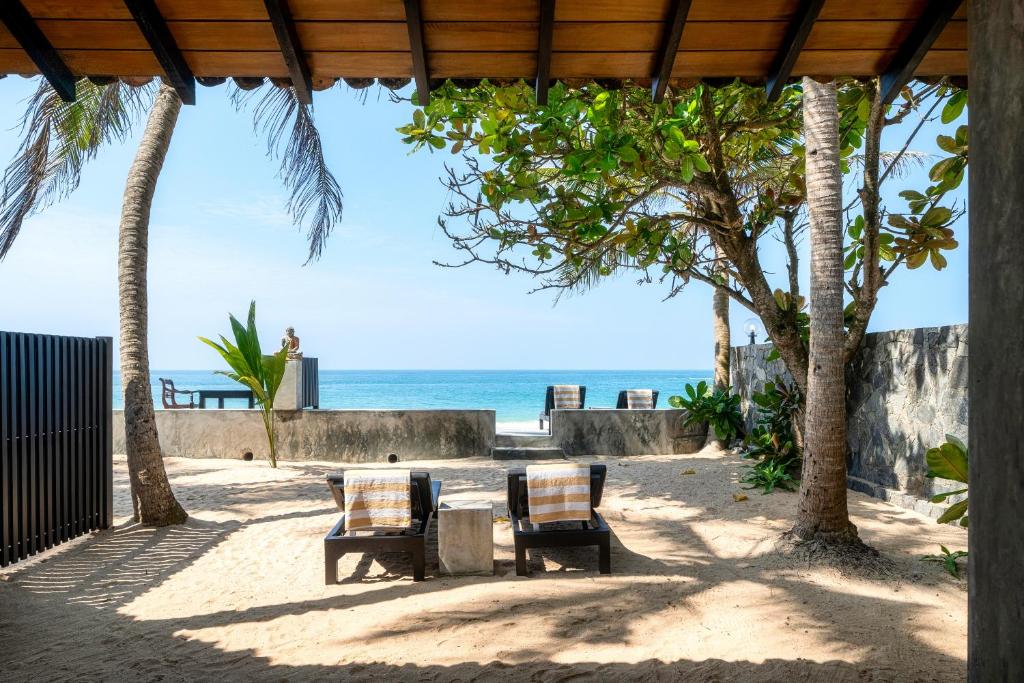 einen Tisch und Stühle am Strand mit Meerblick in der Unterkunft Red Parrot Beach Villa in Ambalangoda