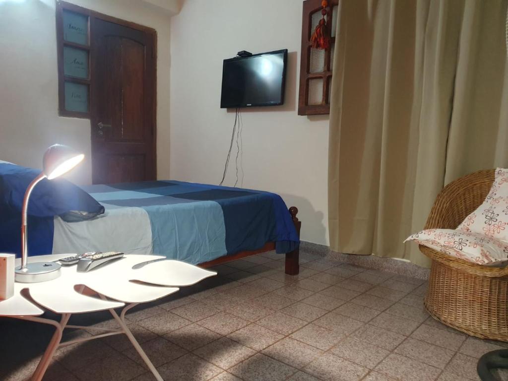 1 dormitorio con 1 cama, TV y silla en Dúplex La Nona en Salta