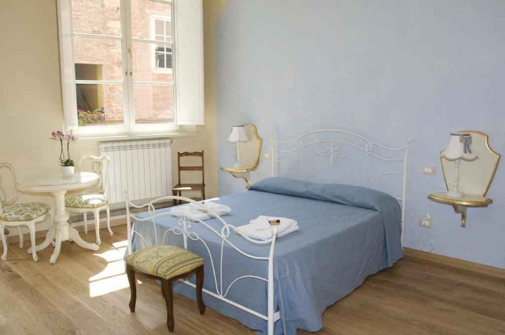 a bedroom with a blue bed and a table and chairs at B&B Anfiteatro in Lucca