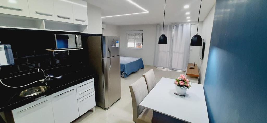 a kitchen with a table and a room with a bed at FLAT 22º andar totalmente mobiliado lazer completo in Guarulhos