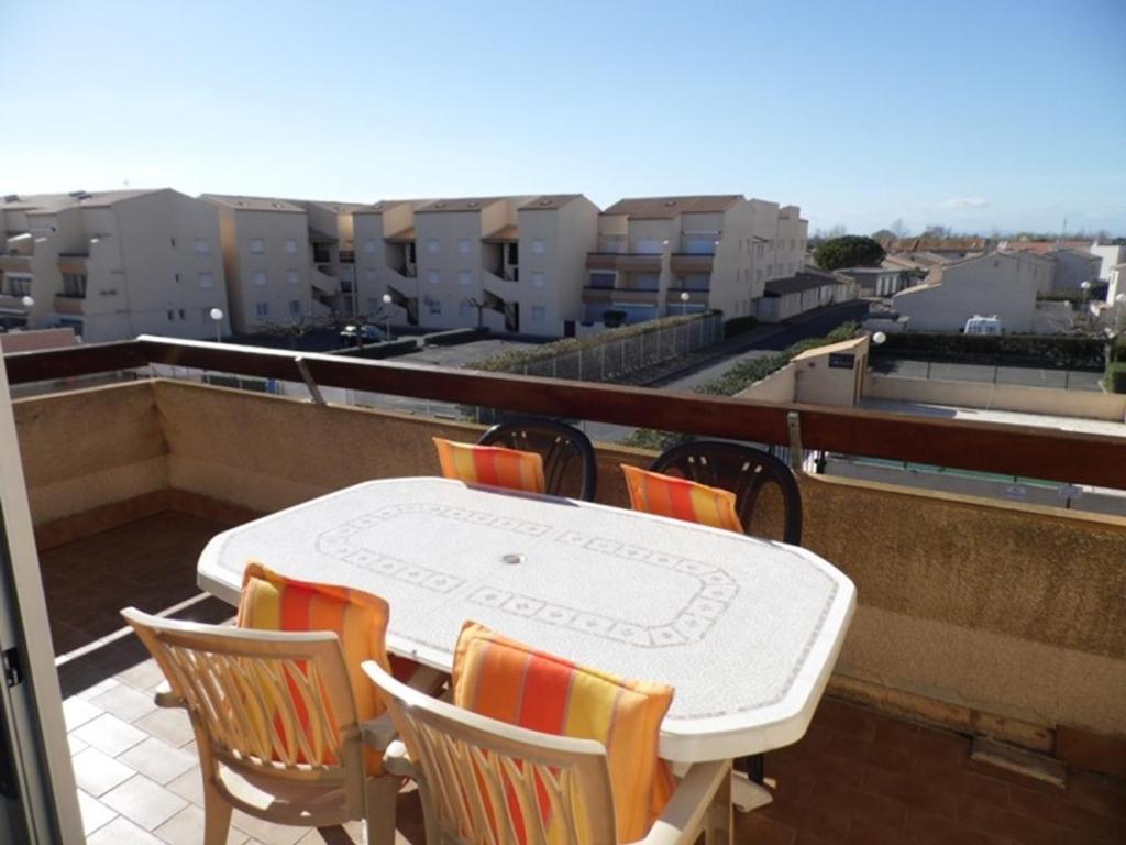 une table blanche et des chaises sur un balcon dans l'établissement Appartement 2 pièces avec mezzanine, terrasse et piscine à Marseillan-Plage - FR-1-326-528, à Marseillan