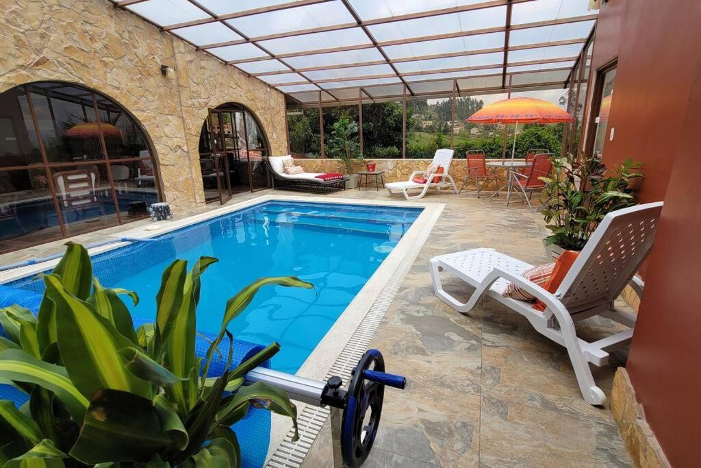 a swimming pool with two chairs and an umbrella at Excepcional Villa dulce Raquel chimenea y horno in Cuenca