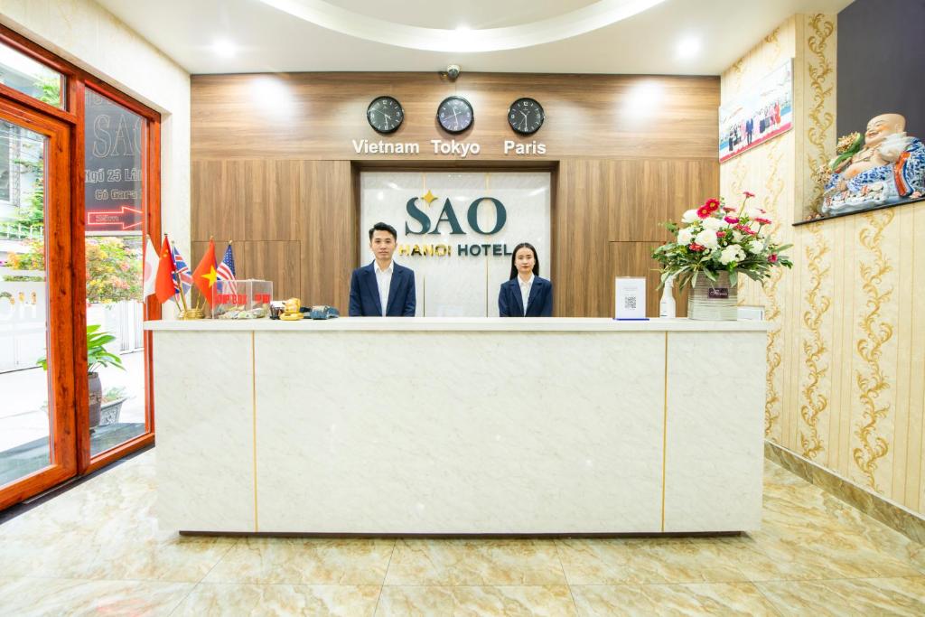 zwei Personen stehen an der Rezeption eines xoarma Hotels in der Unterkunft Khách Sạn Sao in Hanoi