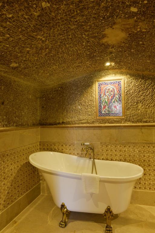 a bath tub in a bathroom with a mosaic wall at Goreme Suites by AZA in Göreme