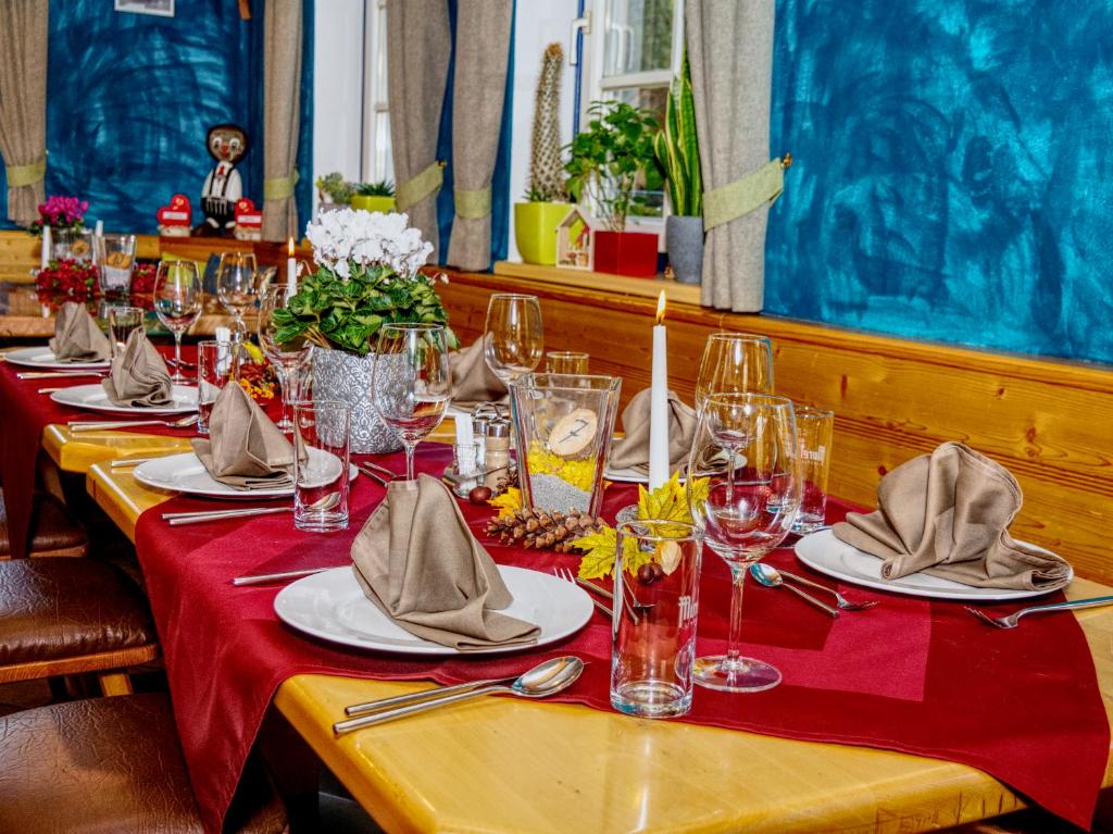 a long table with red table cloth and glasses and napkins at Gasthof zum Postwirt in Predlitz