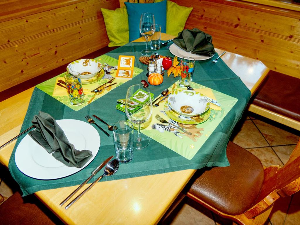 a table with a green table cloth and plates and glasses at Gasthof zum Postwirt in Predlitz