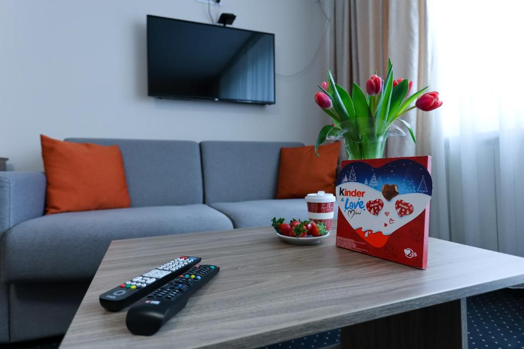 une table avec deux télécommandes et un vase de fleurs dans l'établissement Smeštaj Tank, Pančevo, 