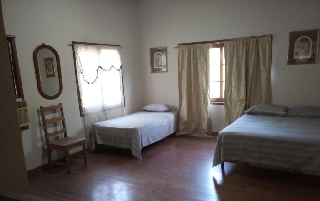 a bedroom with two beds and a chair and a window at Casa del Campo in Tela