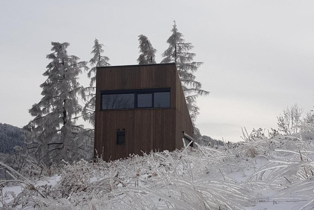 een klein gebouw bovenop een met sneeuw bedekte heuvel bij Domek na wzgórzu 