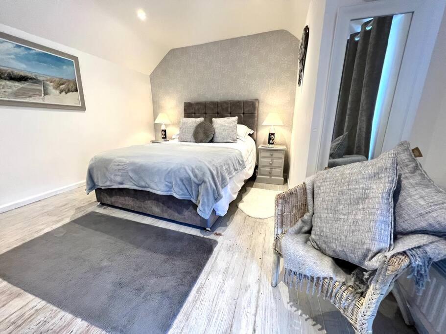 a bedroom with a large bed and a chair at Anchor Cottage - beautiful two bedroom cottage in the heart of Holt in Holt
