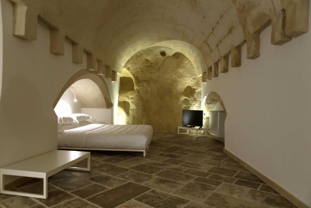 sypialnia z łóżkiem i telewizorem w tunelu w obiekcie Pietragialla w mieście Matera