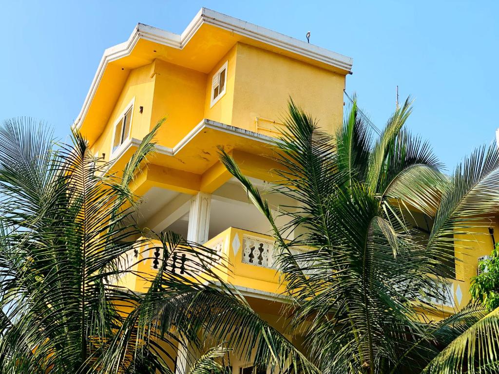 a yellow building with palm trees in front of it at Mamta courtyard anjuna in Anjuna